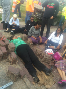 Freedmen's Town Preservation Coalition President, Dorris Ellis Robinson, laid down in the trench surrounded by FTPC members on the bricks.