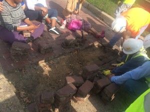 Concerned citizens sit on the bricks to prevent further removal.